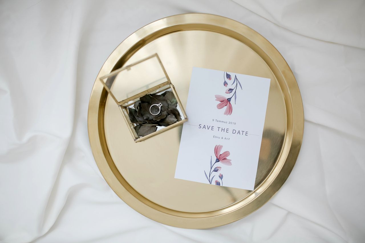 An elegant save the date card and engagement ring on a gold tray, perfect for weddings.